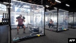 People exercise at Inspire South Bay Fitness behind plastic sheets in their workout pods while observing social distancing on June 15, 2020 in Redondo Beach, California, as the gym reopens today under California's coronavirus Phase 3 reopening guidelines.