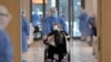 Seorang pekerja medis mengenakan pakaian pelindung khusus, memindahkan pasien virus korona baru dengan kursi roda di sebuah rumah sakit di Wuhan, provinsi Hubei, China 10 Februari 2020. (Foto: China Daily via REUTERS)