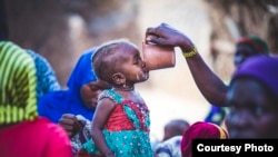 FILE - A toddler samples millet porridge after a cooking demonstration in Zinder, Niger, where a Mercy Corps program helps people grow and sell more nutritous food. The international relief group is a USAID partner. (Sean Sheridan photo courtesy of Mercy Corps)