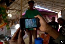 Rohingya Muslim refugee Mohammad Karim, 26, shows a mobile video of Gu Dar Pyin's massacre inside his kiosk in Kutupalong refugee camp, Bangladesh, Jan. 14, 2018.