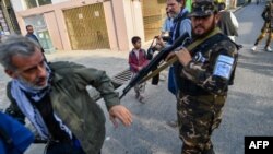 FILE - A member of the Taliban special forces pushes a journalist (L) covering a demonstration by women protesters outside a school in Kabul, Afghanistan, Sept. 30, 2021. 