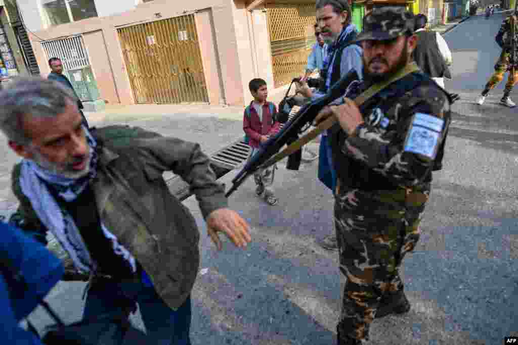 A member of the Taliban special forces pushes a journalist covering a demonstration by women protesters outside a school in Kabul, Afghanistan.