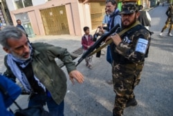 FILE - A member of the Taliban special forces pushes a journalist (L) covering a demonstration by women protestors outside a school in Kabul on September 30, 2021.