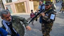 A member of the Taliban special forces pushes a journalist (L) covering a demonstration by women protestors outside a school in Kabul on September 30, 2021.