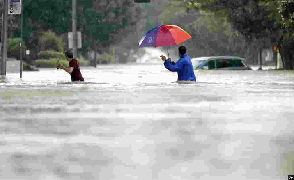 Moses Juarez, left, and Anselmo Padilla wade through floodwaters from Tropical Storm Harvey, in Houston, Texas, Aug. 27, 2017.