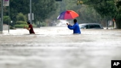 德克萨斯州两名休斯敦居民在哈维飓风来袭时过马路。
（2017年8月27日）