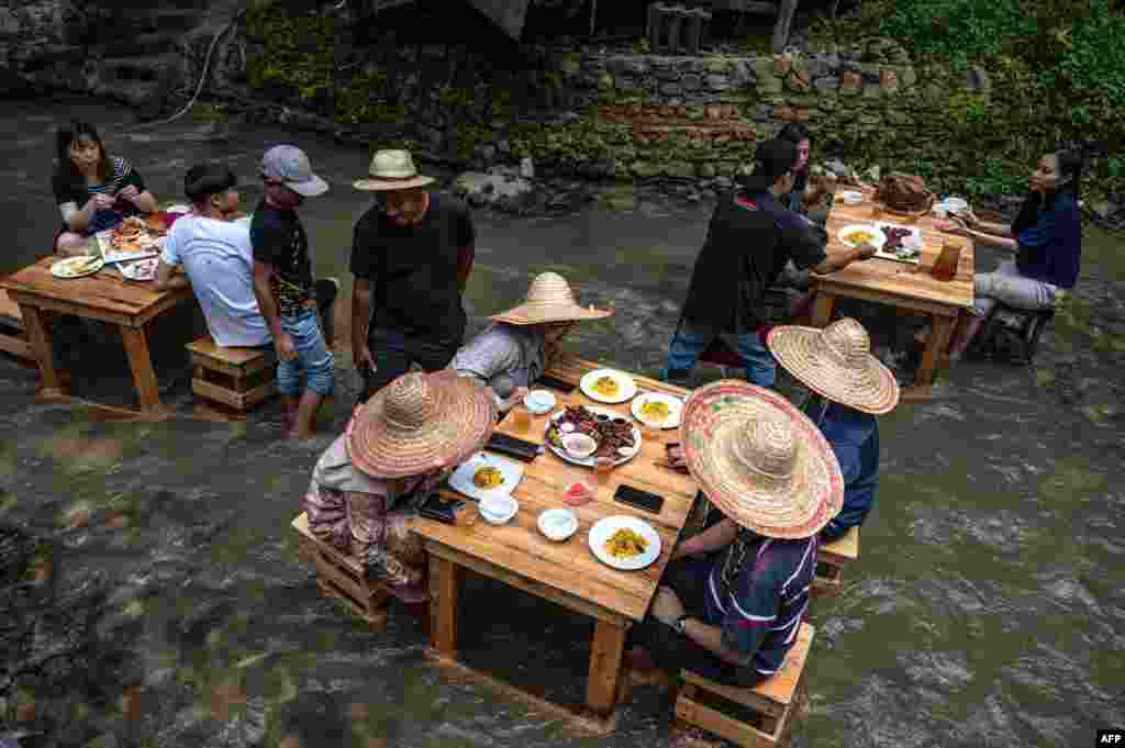 People eat a meal at a restaurant with tables in a stream in Kampung Kemensah on the outskirts of Kuala Lumpur, Malaysia.