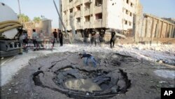 An Egyptian worker checks a hole believed to be caused by a car bombing in the street outside the national security building in the Shubra el-Kheima neighborhood of Cairo, Aug. 20, 2015.