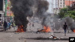 Congo Violence: People walk near burning debris during election protests in Kinshasa, Democratic Republic of Congo, Monday, Sept. 19, 2016. 