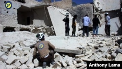 지난 25일 시리아 알레포의 반군 장악 지역인 부스탄알카스르에서, 민방위대 '화이트헬멧' 대원들이 공습으로 무너진 건물 잔해를 살피고 있다.