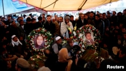 Pictures of Afghan journalist Sardar Ahmad of Agence France-Presse (R) and his wife are placed on their graves in Kabul March 23, 2014.