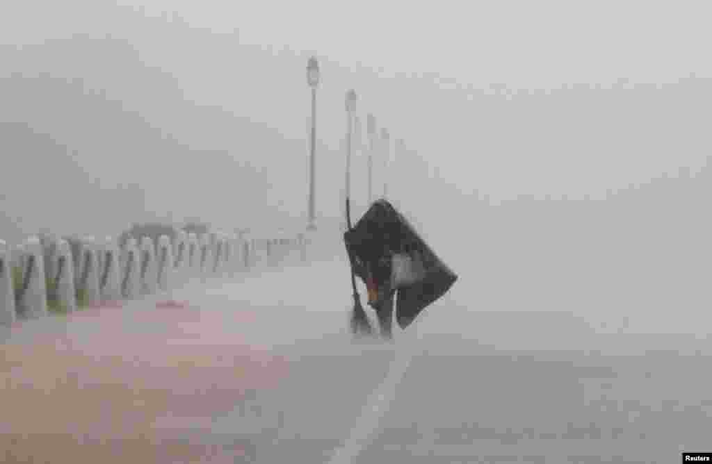 A woman covers herself with a plastic sheet as she walks during heavy rains in New Delhi, India.