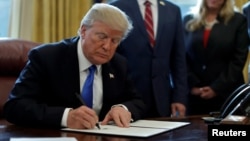 FILE - U.S. President Donald Trump signs documents in the Oval Office of the White House in Washington, Jan. 9, 2018. 