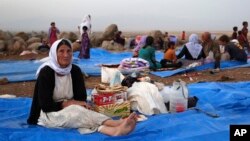 FILE - In this Sunday, Aug. 10, 2014 file photo, displaced Iraqis from the Yazidi community settle at a camp at Derike, Syria.