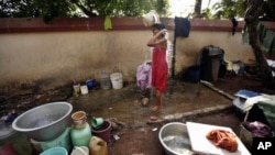 A woman bathes using water collected from various areas on World Water Day at a slum in Bhubaneswar, India, March 22, 2012. 