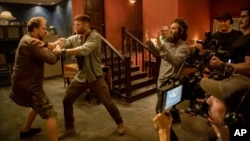 This image provided by Netflix shows actors David Harbour, from left, and Chris Hemsworth being directed by Sam Hargrave for a scene in the action film "Extraction." Hargrave, who was Chris Evans' stunt double on “Captain America” and Hugh Jackman's doubl