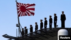 FILE - Sailors stand on the deck of the Izumo warship as it departs from the harbor of the Japan United Marine shipyard in Yokohama, south of Tokyo.