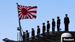 2015年3月25日，日本海军站在即将起航的出云级护卫舰甲板上，这艘军舰即将驶离东京南部的横滨日本联合海上造船厂。