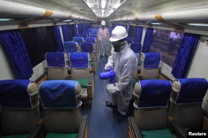 Seorang petugas menyemprotkan cairan disinfektang di dalam kereta untuk mencegah penyebaran virus corona (COVID-19), di Surabaya, Jawa Timur, 15 Maret 2020. (Foto: Reuters)