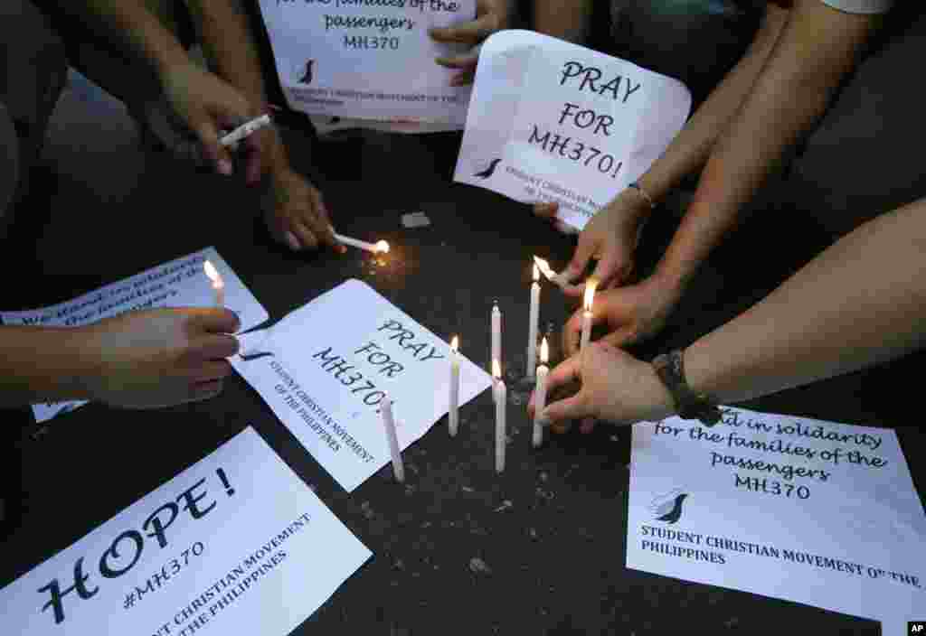 Para siswa menyalakan lilin untuk mengekspresikan harapan dan solidaritas bagi penumpang pesawat Malaysia Airlines yang hilang, Manila, Filipina, 13 Maret 2014.