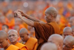 Seorang biksu mengambil gambar sementara biksu dan samanera berkumpul di kuil Wat Phra Dhammakaya. (Foto: REUTERS/Jorge Silva)