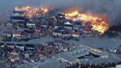 Houses burn in a flooded area of Natori City in northern Japan after the earthquake and tsunami on Friday