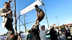 FILE - Men are trying to prevent the execution of convict pardoned by the family of a policeman he was convicted of killing, in Mashhad, northeastern Iran, May 8, 2013.