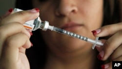 Judith Garcia, 19, fills a syringe as she prepares to give herself an injection of insulin at her home in the Los Angeles suburb of Commerce, Calif., April 29, 2012