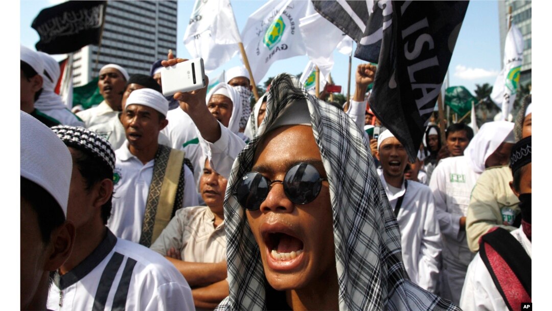 FILE - Members of the militant Islamic Defenders Front (FPI) shout slogan during a demontration in Jakarta, Indonesia.