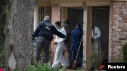 Homeland Security Investigations (HSI) personnel escort a man wearing handcuffs to a transport bus from a residence in southwest Houston, Texas, U.S., April 30, 2021. 