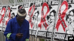 FILE - A man makes a call on his mobile phone as he walks past World AIDS Day banners in Johannesburg, South Africa, Dec. 1, 2014.