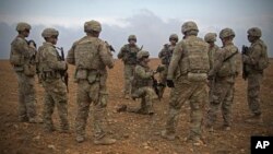 FILE - In this photo released by the U.S. Army, U.S. soldiers gather for a briefing during a combined joint patrol rehearsal in Manbij, Syria, Nov. 7, 2018.