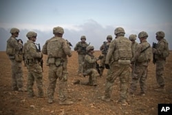FILE - U.S. soldiers gather for a briefing during a patrol rehearsal in Manbij, Syria, Nov. 7, 2018.