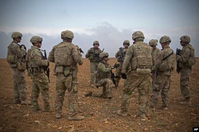 FILE - U.S. soldiers gather for a briefing during a patrol rehearsal in Manbij, Syria, Nov. 7, 2018.