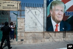 A woman watches a motorcade carrying President Donald Trump to a meeting with Palestinian President Mahmoud Abbas, May 23, 2017, in the West Bank City of Bethlehem.