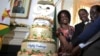 FILE: Zimbabwean President Robert Mugabe (R) is helped by his wife Grace (L) and son Chatunga (C) to cut a cake to celebrate his 92nd birthday at State House in Harare, Feb. 22, 2016. 