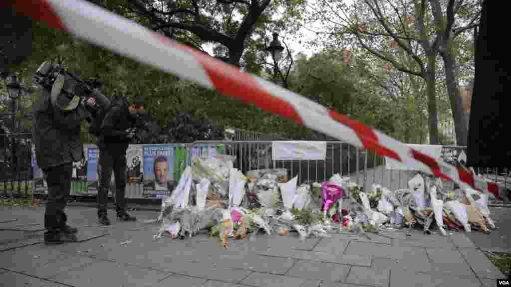 Journalists examine a memorial outside the Bataclan Concert Hall a day after more than 120 people were killed in a series of attacks in Paris, Nov. 14, 2015.