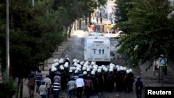 Kurdish protesters throw stones as they clash with riot police (foreground) in Diyarbakir, Turkey, Oct. 8, 2014. 