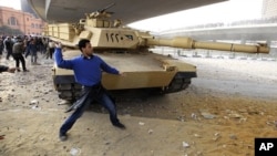 An opposition supporter throws a rock in front of a tank during rioting with pro-Mubarak demonstrators near Tahrir Square in Cairo, February 3, 2011