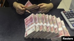 FILE - A clerk counts 100 Chinese yuan banknotes at a branch of China Merchants Bank in Hefei, Anhui province April 20, 2015.