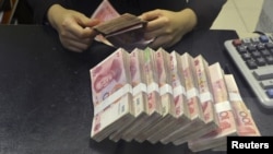 FILE - A clerk counts 100 Chinese yuan banknotes at a branch of China Merchants Bank in Hefei, Anhui province April 20, 2015.