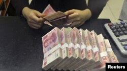 FILE - A clerk counts 100 Chinese yuan banknotes at a branch of China Merchants Bank in Hefei, Anhui province, April 20, 2015.