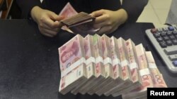 Pegawai China Merchants Bank menghitung lembaran uang 100 yuan di Hefei, provinsi Anhui.