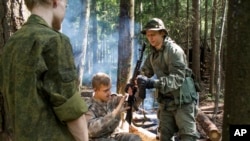 In this photo taken Aug. 21, 2016, from left, Sergei, Andrei and Artem assemble a Kalashnikov before shooting practice in their makeshift camp organized by the ultra-nationalist Eurasian Youth Union, on the outskirts of Moscow, Russia.