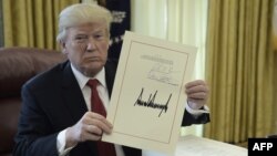 도널드 트럼프 미국 대통령이 22일 백악관 집무실에서 감세안에 서명한 후 문서를 들어보이고 있다.