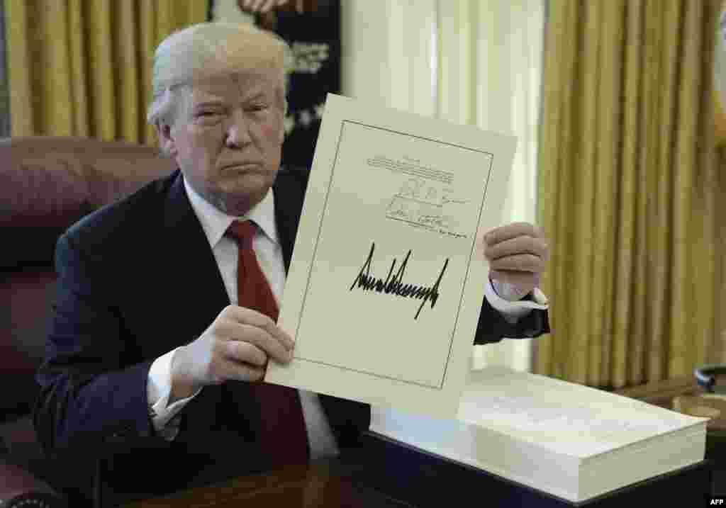 U.S. President Donald Trump holds up a document during an event to sign the Tax Cut and Reform Bill in the Oval Office at The White House in Washington, D.C.