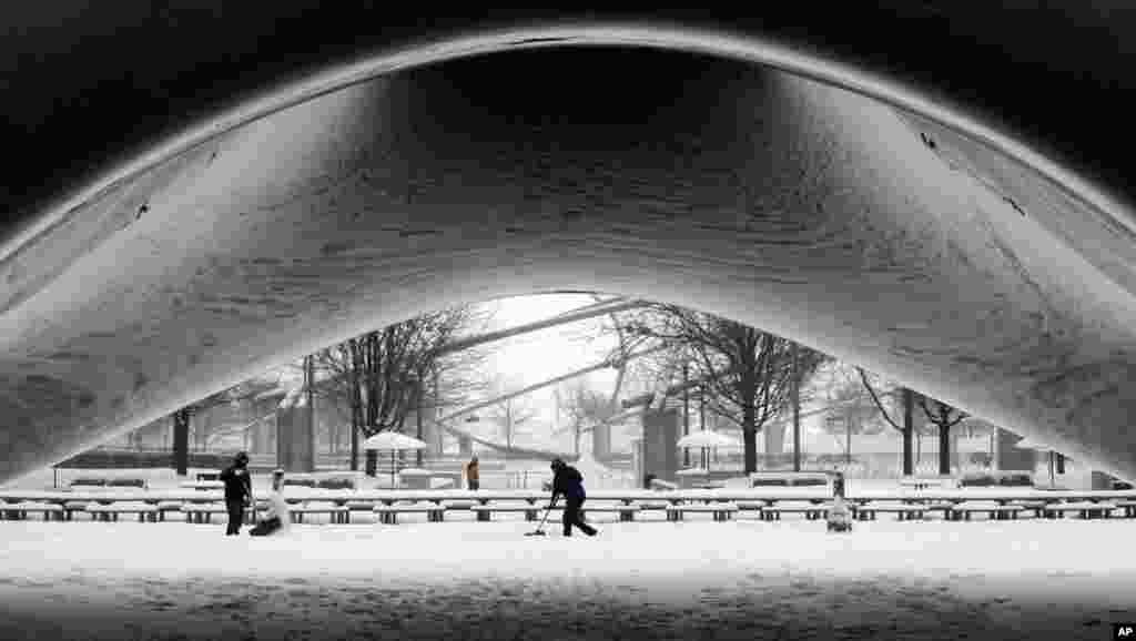 Nhân viên công viên dọn tuyết quanh tác phẩm điêu khắc bằng thép Cổng Mây của điêu khắc gia Annish Kapoor tại Công viên Milllenium trong khi tuyết tiếp tục rơi trong trung tâm thành phố Chicago, tiểu bang Ilinois, Hoa Kỳ