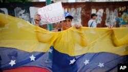 Una mujer muestra un rótulo referente a la muerte de Juan Pablo Pernalete, que falleció a consecuencia del golpe de una bomba lacrimógena que recibió en el pecho.