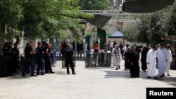 Tourists walk near Israeli police officers and recently installed metal detectors at an entrance to the compound known to Muslims as Noble Sanctuary and to Jews as Temple Mount in Jerusalem's Old City, July 23, 2017. 