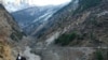 Orang-orang berjalan melewati bendungan yang hancur setelah gletser Himalaya pecah dan menabrak bendungan di Desa Raini Chak Lata di distrik Chamoli, negara bagian utara Uttarakhand, India, 7 Februari 2021. (Foto: Reuters)